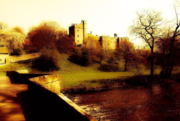 A digital reconstruction or artist's impression of a fortified Mississippian village, showing palisade walls, watchtowers, and a central mound, under a dramatic sunset.
