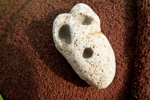 Close-up of a human skull specimen from an archaeological dig, clearly showing a healed depression fracture on the frontal bone, indicative of blunt-force trauma. The bone is light brown, suggesting it's an ancient artifact, with careful archaeological tools visible in the blurred background.
