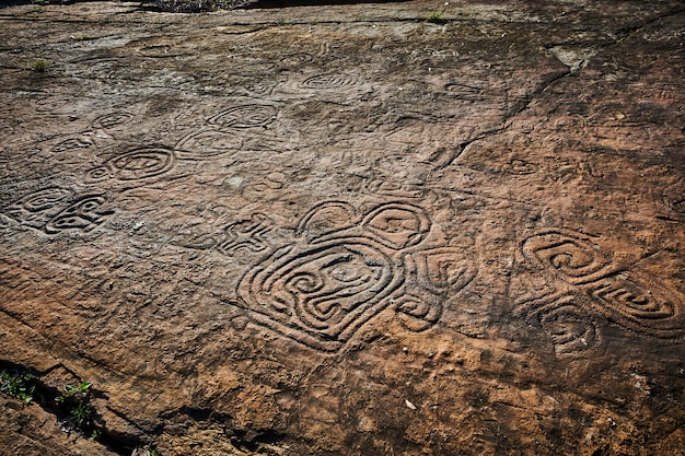 A digital rendering of a petroglyph site in the Southwest, showing various symbols carved into a sandstone cliff face. The image uses augmented reality to highlight possible interpretations of the symbols, overlaying them with explanations and connections to known Native American languages from that region, thereby reflecting the complexities of Decoding Ancient Languages: New Insights from Archaeological Inscriptions Found in the US.