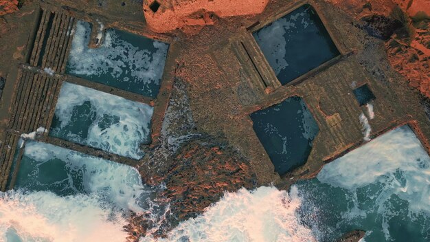 An aerial photograph showing a river overflowing its banks and flooding an archaeological site. The site contains the remnants of an ancient city, with structures partially submerged in water. The image highlights the vulnerability of archaeological sites located near rivers and coastlines to increased flooding due to rising sea levels and extreme weather events associated with The Impact of Climate Change on Archaeological Sites: Protecting Our Heritage from Erosion and Rising Sea Levels.
