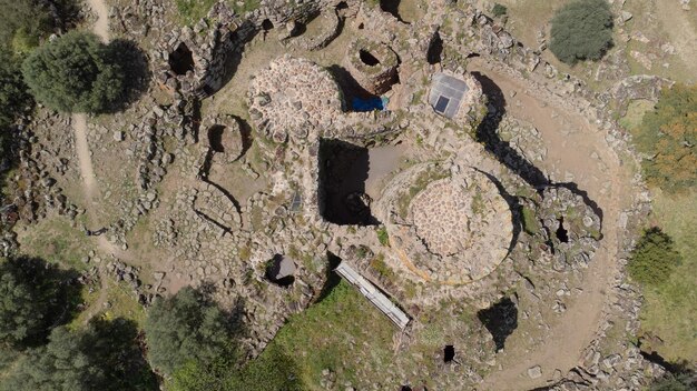 An aerial photograph of an archaeological dig site showing the excavated foundations of several ancient residential homes. Various artifacts, such as pottery shards and tools, are visible within the home outlines. This represents The Archaeology of Everyday Life: Reconstructing the Lives of Ordinary People from the Past through residential structures.