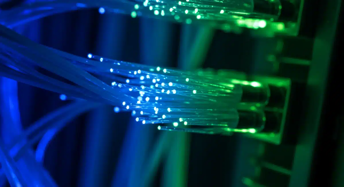 Close-up of glowing fiber optic cables in a data center environment.