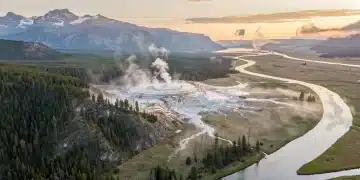 Yellowstone National Park landscape with geysers and forests under a changing sky